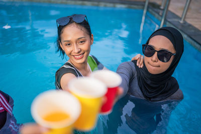 Portrait of smiling young woman with balloons in swimming pool