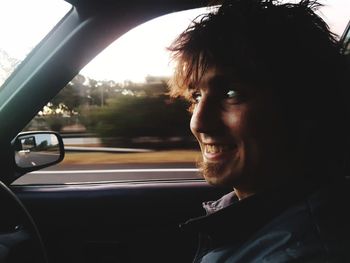 Close-up of smiling young man traveling in car