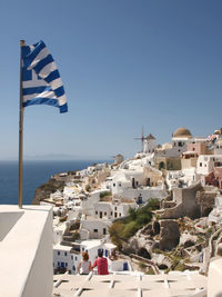 Buildings by sea against clear blue sky