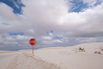 Road sign in desert against sky