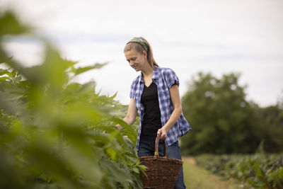 Young woman standing against plants