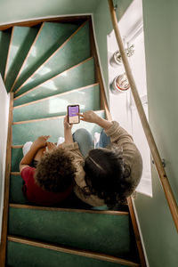 Mother showing home automation app on smart phone to son while sitting on staircase