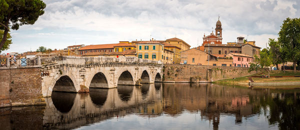 Arch bridge over river against buildings in city