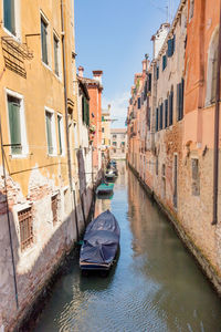 Boats moored in canal amidst buildings in city