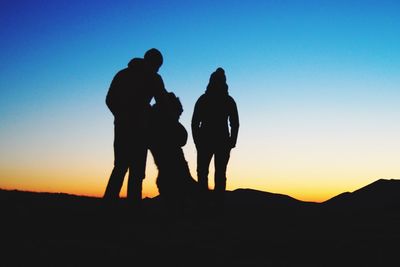 Silhouette friends standing against clear sky during sunset