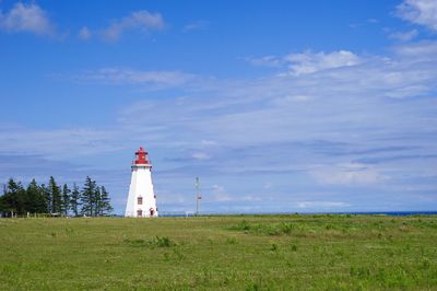 Lighthouse on field against sky