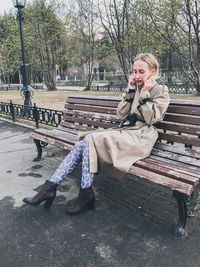 Portrait of woman sitting on bench in park