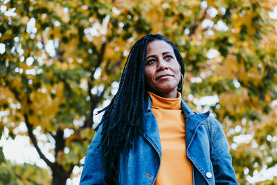 Portrait of smiling woman standing against tree