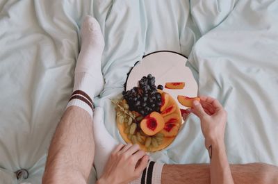 Midsection of man holding ice cream on bed