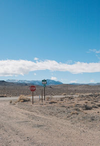 Road sign in desert against blue sky