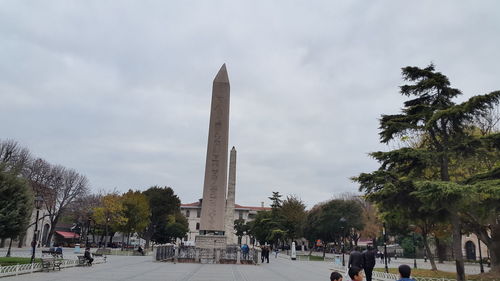 Tourists at monument against cloudy sky