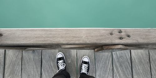 Low section of person standing on wooden floor