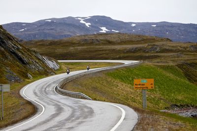 People riding motorcycle on road against sky