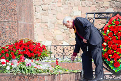 Side view of man standing against red wall