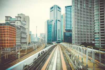 Railroad tracks amidst buildings in city against sky