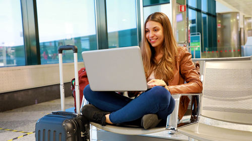 Young woman using phone while sitting on seat