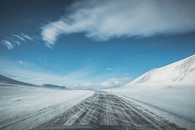 Road leading towards snowcapped mountain against sky