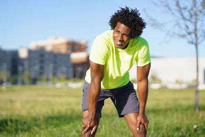 Young man looking away while standing on field