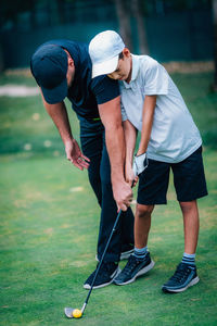 Rear view of men standing on golf course