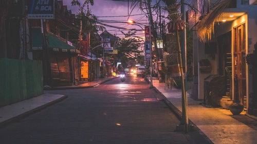 Illuminated street amidst buildings in city at night