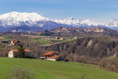 Houses on field by mountain against sky