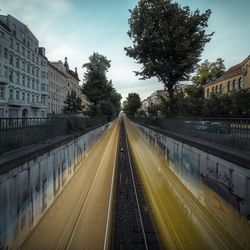 Blurred motion of trains on railroad tracks in city against sky