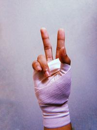 Cropped hand with bandage against gray background