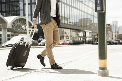 Low section of businessman with luggage walking outside railway station