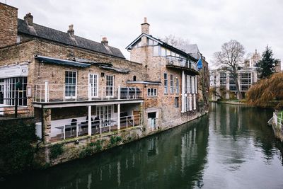 Buildings by river against sky