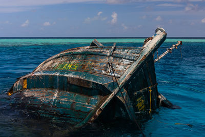 Abandoned boat on sea against sky