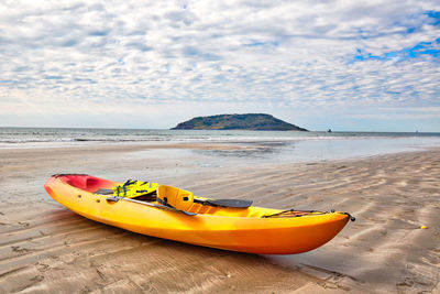 Yellow boat on beach against sky