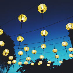 Low angle view of illuminated lanterns hanging against clear sky