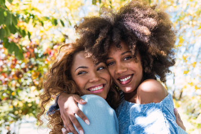 Two female afro american and happy best friends hugging each other and laughing in the park