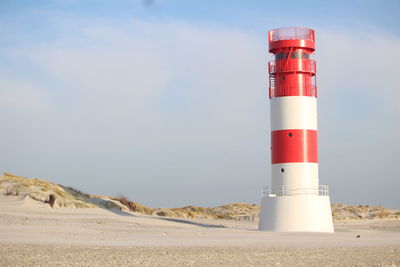 Lighthouse on beach against sky