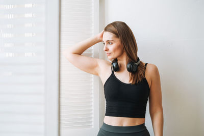 Young woman standing against wall