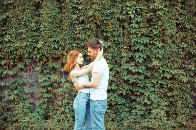 Young couple standing against plants