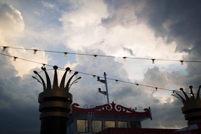 Low angle view of birds perching on cable against sky