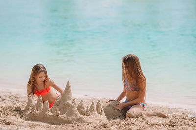 Sisters plying with sand on beach