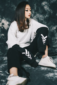 Young woman looking away while sitting outdoors