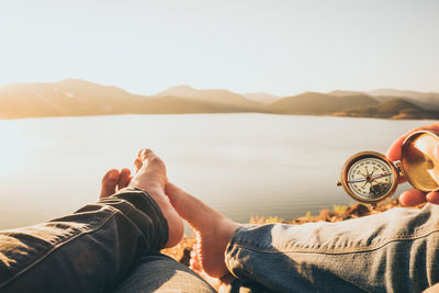 Low section of people lying on shore against sky