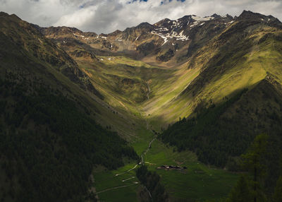 Scenic alpine view of green valley and mountains against sky