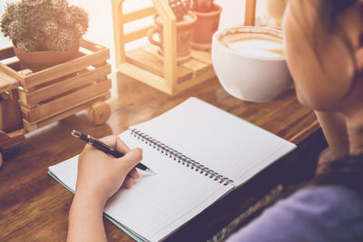 Midsection of woman reading book on table