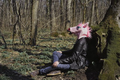 Man wearing unicorn mask while sitting on field