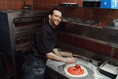 Side view of male chef making pizza in restaurant kitchen