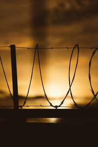 Silhouette fence against sky during sunset