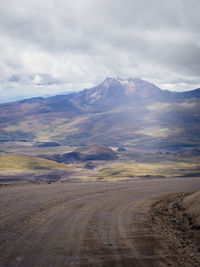 Scenic view of road by mountains against sky