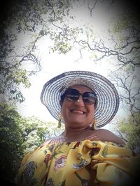 Portrait of smiling young woman against trees