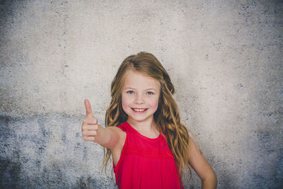 Portrait of a smiling girl standing against wall