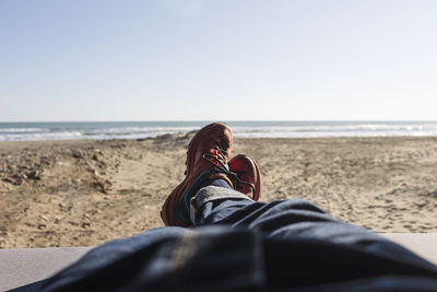 Man's legs in blue jeans and hiking shoes lying inside a van on the beach. loneliness man tourism