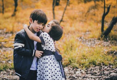 Sister kissing on brother cheek at forest